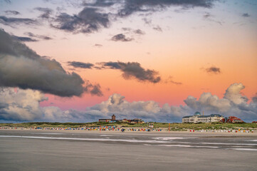 Strandabschnitt auf der Nordseeinsel Juist mit Bauten und dramatischen Abendhimmel im Sommer