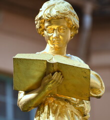 Goldglänzende Knabenfigur mit Buch auf dem Bürgerschulbrunnen 