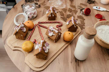 Christmas cooking gingerbread houses and ginger cookies on the kitchen table with tangerines.