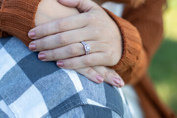 Close up photograph of bride's hand resting on blue plaid shirt with beautiful silver ring with diamonds. Manicured fingers with double ring. Hands resting on man's plaid shirt. 