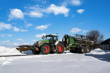 Wintereinbruch in der Landwirtschaft, Traktor mit Güllefass im Schnee.