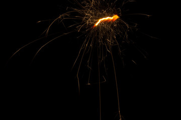 Sparks of sparkler on a long exposure fly on a black background forming lines.