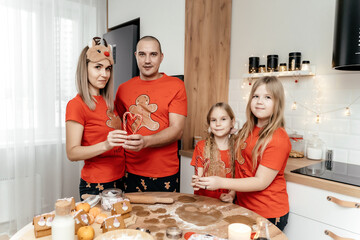 A family in Christmas pajamas cooking ginger cookies in the kitchen
