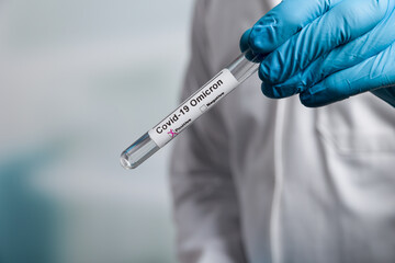 Close up of doctor's hands in medical gloves holding a test tube after virus analysis with omicron result markers