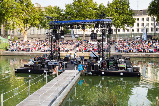 Spectacle musical sur une sc&egrave;ne flottant sur une rivi&egrave;re, avec nombreux spectateurs sur des gradins. RDV de l'Erdre, Nantes
