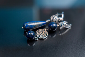 Handmade jewelry made of natural stones. Blue earrings made of lapis lazuli stone. Selective focus