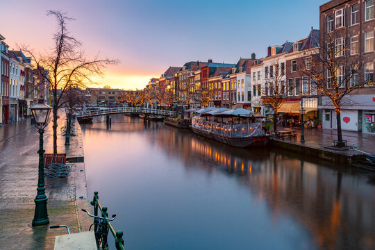 Leiden canal Oude Rijn with trees in Christmas illumination at sunrise, South Holland, Netherlands. © Kavalenkava