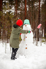 Fototapeta na wymiar Girl of nine years old on winter walk near snowman