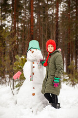 Girl of nine years old   on   winter walk near   snowman