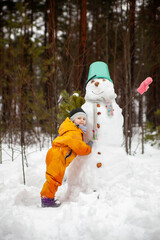 Fototapeta na wymiar Little todler on winter walk near snowman
