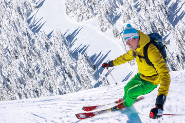 Fototapeta na wymiar Skier skiing downhill in high mountains against blue sky