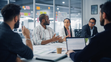 Diverse Modern Office: Portrait of Successful Black Businessman Leads Meeting, talks about Company Growth. Digital Entrepreneurs Work on e-Commerce Project. Creative Multi-Ethnic Business Workplace