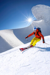 Fototapeta Skier skiing downhill in high mountains against blue sky obraz