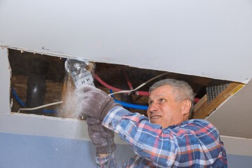 Repair of home on angle hand electric power tools on cutting gypsum drywall sheet with damaged...