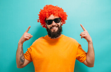 Funny bearded hipster man in wig. Happy stylish man with red hair.