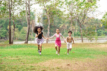 Fototapeta na wymiar Small group of a happy children run through the park in the background of grass and trees. Children's outdoor games, vacations, weekend, Children's Day
