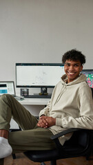 Cheerful young guy, mixed race trader work from home using laptop and computer, sitting in modern...