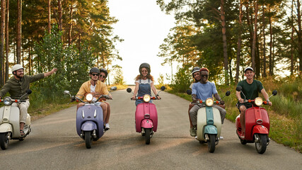Happy young multiracial people riding retro scooters