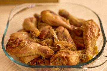 a glass bowl with fried chicken legs on a table