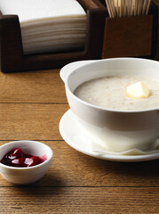 Plate of porridge with cherry jam, cake and butter on wooden table. Breakfast at the hotel, cafe, restaurant. Copy space. Morning. Food photography. Russian breakfast. Milk porridge for children. 