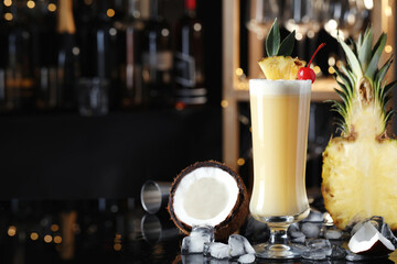Tasty Pina Colada cocktail and ingredients on bar countertop, space for text