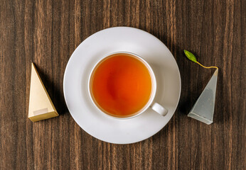 A cup of strong black hot tea forte isolated on dark wooden background top view