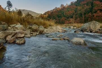 Fototapeta na wymiar Beautiful Reshi River water flowing through stones and rocks at dawn, Sikkim, India. Reshi is one of the most famous rivers of Sikkim flowing through the state and serving water to many local people.