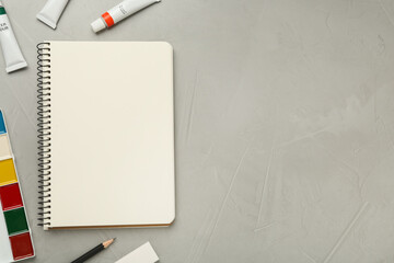 Flat lay composition with blank sketchbook on light grey stone table. Space for text
