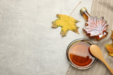 Flat lay composition with tasty maple syrup and dry leaves on light grey table, space for text - obrazy, fototapety, plakaty