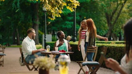 Charismatic couple multiracial black woman and blonde hair guy have a meeting with other friends two beautiful ladies they meet at the cafe