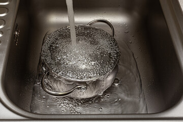 tap water is poured into the pan in the sink - obrazy, fototapety, plakaty