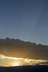 The sun between the mountain and a dense cloud at sunset, near he colonial town of Villa de Leyva, in central Colombia.