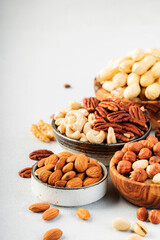 Nuts in bowls. Cashews, hazelnuts, walnuts, pecans, almonds and other. Healthy food snack mix on gray table background, copy space