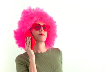 Woman wearing a pink wig and heart shaped glasses using smartphone on white background