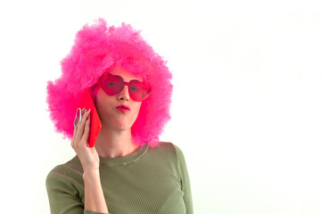 Woman wearing a pink wig and heart shaped glasses using smartphone on white background