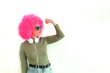 Woman wearing a pink wig and heart shaped glasses using headphones. 