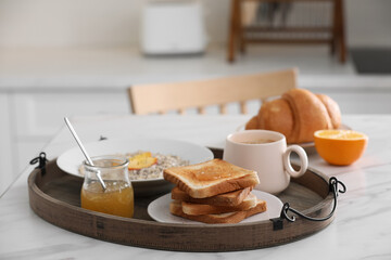 Wooden tray with delicious breakfast on white marble table in kitchen, space for text