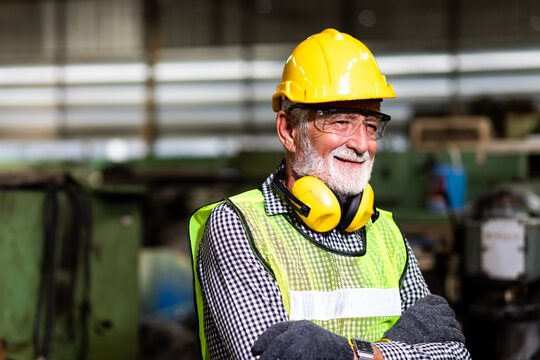 Portrait of senior engineering architect builder wearing protective hardhat working at Metal lathe industrial manufacturing factory. Engineer Operating  lathe Machinery. Elderly people