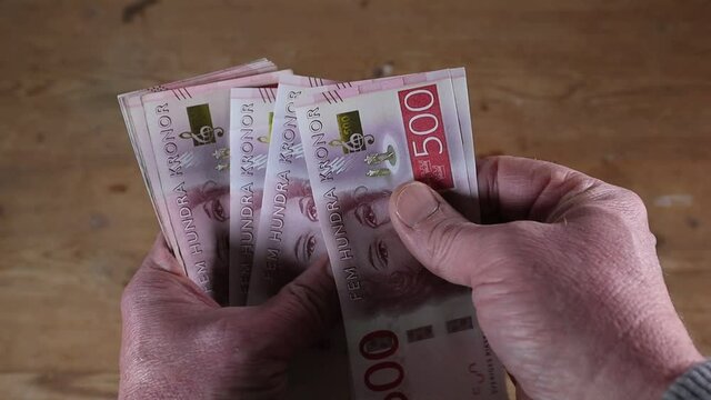 A hand fans out a stack of Swedish 500 kr notes.