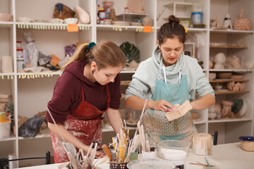 Young women enjoying working with ceramics at pottery workshop