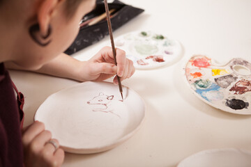 Obraz na płótnie Canvas Cropped rear view close up of a female artist painting on a ceramic plate