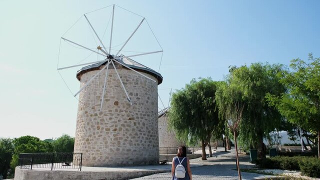 Alaçatı, a small resort town in Turkey's Izmir province. Young tourist woman is walking among historic windmills.