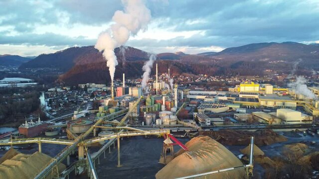 Aerial view of a huge paper factory facility in Austria during sunset. Lots of steam coming out of chimneys and pollute the air	
