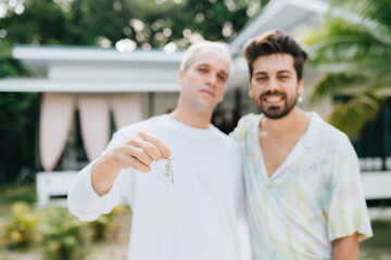 Gay couple standing and holding keys of thier new house