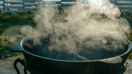 Big pot with street food preparing on fire outdoors. Kitchen outdoors. Metal cauldron on the fire.