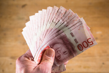 A hand fans out a stack of Swedish 500 kr notes.