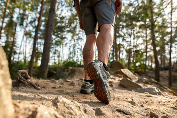 Muscular legs of caucasian man wearing trekking boots - Powered by Adobe