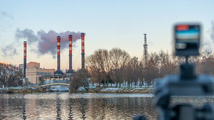 A small camera is filming an industrial plant. Defocused foreground with camera display. Ecological...