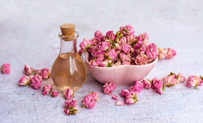 Fototapeta na wymiar Rose essential oil in glass bottle and pink rose flowers . Rose water 