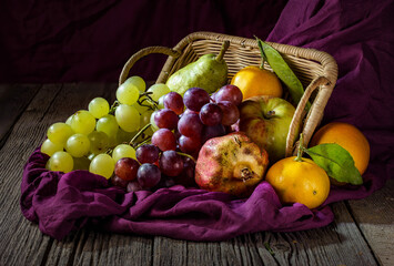 Still life fruits in a basket  on wooden table,pear, apple, pomegranate, mandarin. 